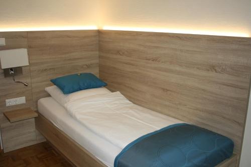 a small bed in a room with a wooden wall at Hotel Schwarzer Adler in Moers