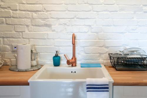 a kitchen counter with a sink and a white brick wall at Bralu street apartments in Liepāja