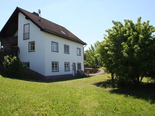 a white house with a tree in the yard at Apartment in Rommersheim with countryside view in Prüm