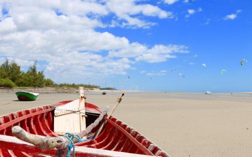 a red boat sitting on a sandy beach at Pousada Kite Guajiru in Itarema