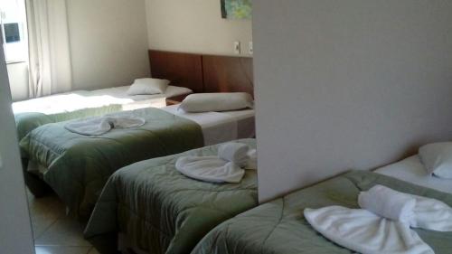 a room with three beds with towels on them at Hotel e Restaurante Bordignon in Joaçaba
