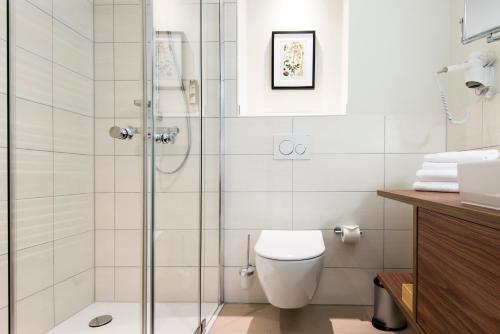 a bathroom with a toilet and a glass shower at Boutique-Hotel Zur alten Post in Büsum