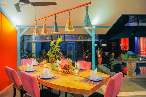 a dining room with a wooden table and pink chairs at Villa Majorelle Bali in Seminyak