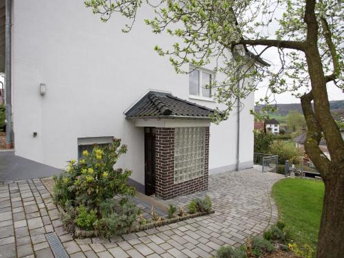 ホムベルクにあるApartment with private terrace in the mountainous region of northern Hesseの庭にレンガ造りの暖炉がある白い家