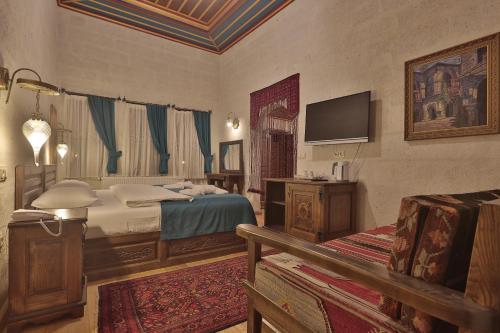 a bedroom with a bed and a tv on the wall at Yoruk Stone House in Nevsehir
