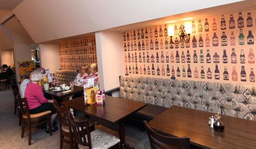 a restaurant with two tables and a wall of wine bottles at Olde House, Chesterfield by Marston's Inns in Chesterfield