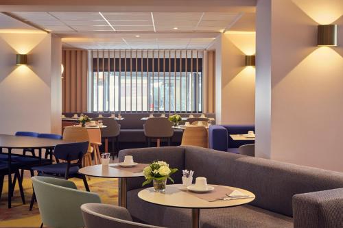 a restaurant with tables and chairs and a couch at Mercure Rouen Centre Cathédrale in Rouen