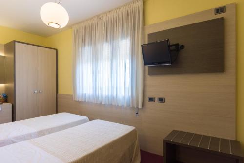 a hotel room with two beds and a tv on the wall at Park Hotel Ristorante Ca' Bianca in Istrana