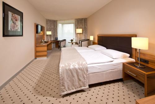 a hotel room with a large bed and a desk at Maritim Hotel Bad Homburg in Bad Homburg vor der Höhe