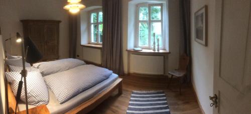 a bedroom with a bed and two windows at Ferienwohnungen im SCHUL & RATHHAUS Obervolkach in Volkach