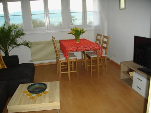 un salon avec une table, des chaises et un tissu de table rouge dans l'établissement Ferienwohnung Gita, à Öhningen