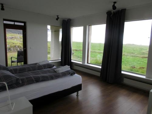 a bedroom with a bed and large windows at Rauðaberg II in Raudaberg