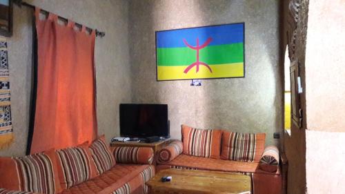 a living room with a couch and a tv at Maison Mirage B&B in Hassilabied