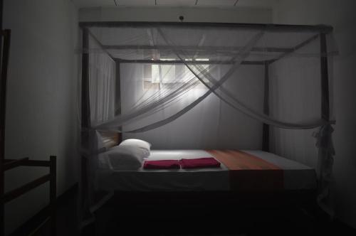 a bedroom with a canopy bed with a window at Chamod Holiday Home in Tangalle