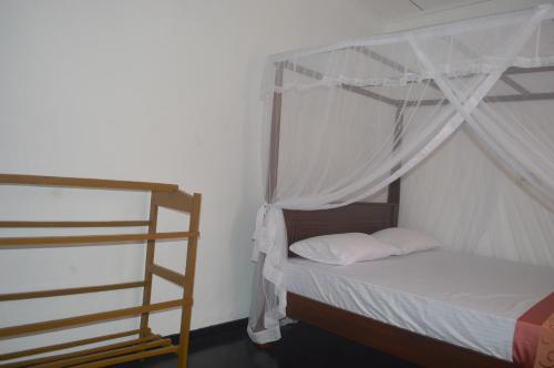 a bedroom with a bed with a canopy and a ladder at Chamod Holiday Home in Tangalle