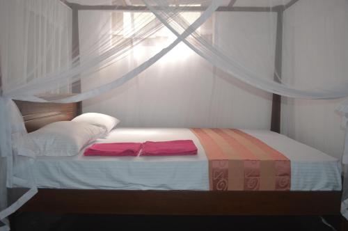 a bed with two red pillows on it in a room at Chamod Holiday Home in Tangalle