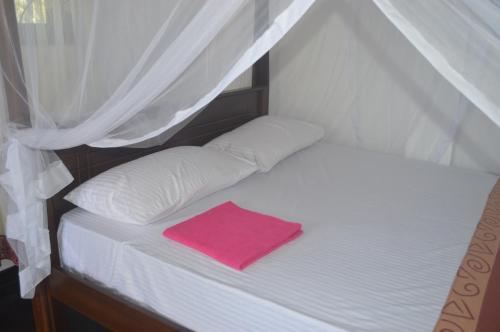 a small bed with a pink towel on it at Chamod Holiday Home in Tangalle
