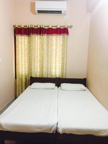 two beds in a room with a window at Mega Tourist Home Palarivattom in Cochin