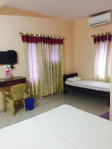 a room with two beds and a desk and a tv at Mega Tourist Home Palarivattom in Cochin