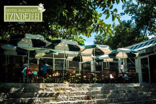 a restaurant with tables and chairs and umbrellas at Hotel Balneario Tzindejeh in Tasquillo