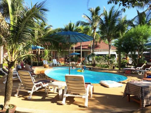 a pool at a resort with chairs and an umbrella at Lanta Seafront Resort in Ko Lanta