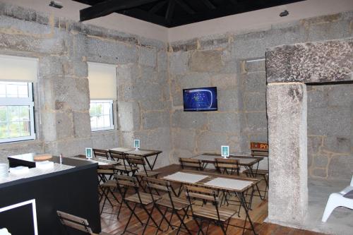 a room with tables and chairs and a tv on a wall at Hostel Casa do Pinheiro in Lagares da Beira