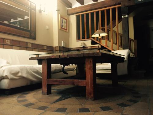 a wooden table in a room with a bed at Hostal Posada La Panadera in Sepúlveda