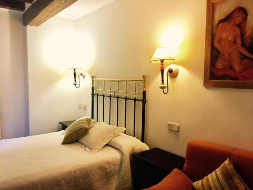 a bedroom with a bed with two lamps and a couch at Hostal Posada La Panadera in Sepúlveda