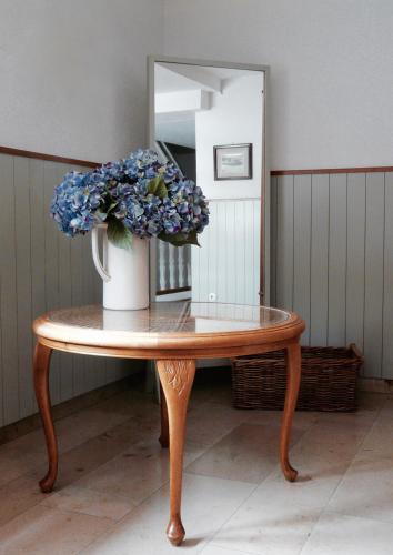 a table with a vase with blue flowers on it at Landfein Big Country House in Winterberg