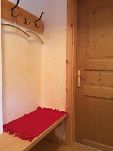 a room with a red blanket on a bench next to a door at Untersteinhof in Mittersill