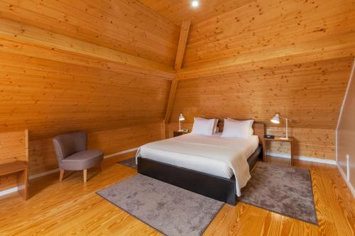 a bedroom with a bed and a chair in a wooden room at BO - Fernandes Tomás in Porto