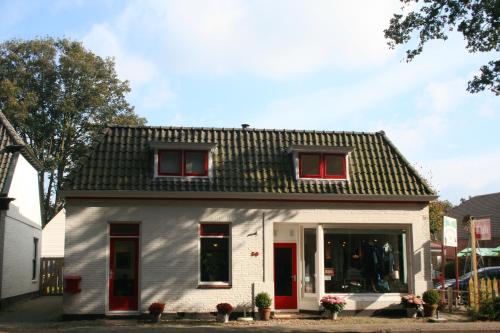 a small white house with red doors and windows at Bed & Breakfast Glimmen in Glimmen