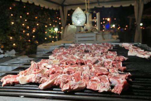 a bunch of meat on a grill with christmas lights at Hotel Sierra Silvana in Selva di Fasano