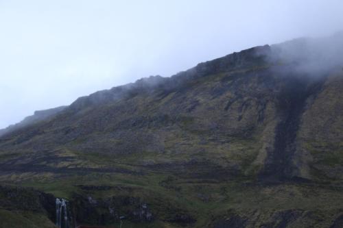 a mountain covered in fog and clouds on top of it at North Star Guesthouse Olafsvik in Ólafsvík
