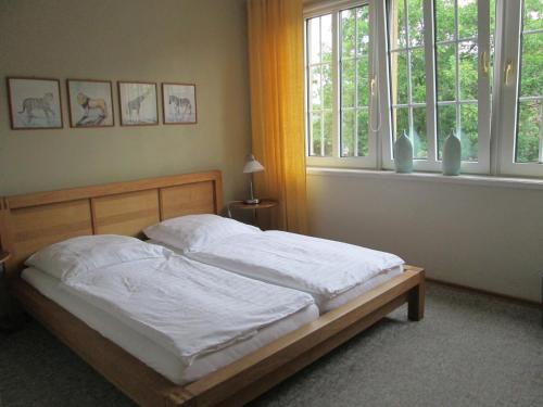 a bedroom with a bed with white sheets and windows at Pension Haus Waldfeucht in Waldfeucht