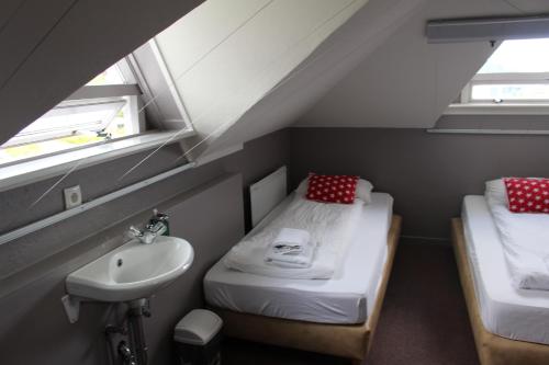 a small room with two beds and a sink at North Star Guesthouse Olafsvik in Ólafsvík