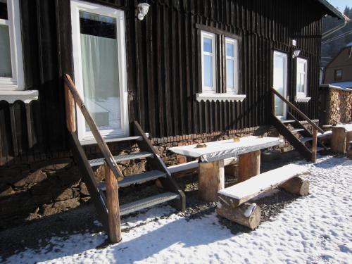 a cabin with a bench and a porch in the snow at Fw. Steindöbra Anno Dazumal in Klingenthal
