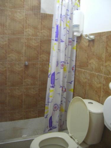 a bathroom with a toilet and a shower curtain at Hostal Palohe Taganga in Taganga
