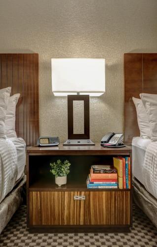 a desk with a lamp on it next to two beds at Garrison Hotel & Suites Dover-Portsmouth, an Ascend Collection Hotel in Dover