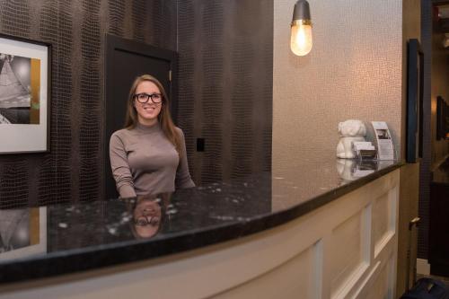 a woman standing in front of a counter in a bathroom at The Garrison Hotel & Suites Dover-Durham, Ascend Hotel Collection in Dover