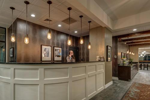 a woman standing at a bar in a hotel lobby at The Garrison Hotel & Suites Dover-Durham, Ascend Hotel Collection in Dover