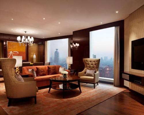 a living room with a couch and chairs and a tv at Hyatt Regency Jinan in Jinan