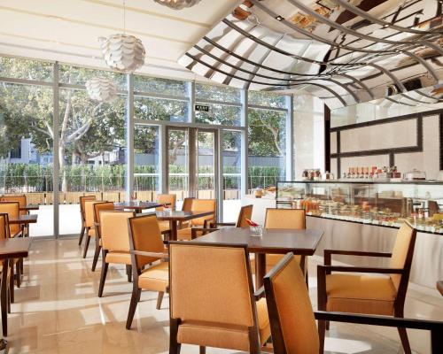 a restaurant with tables and chairs and windows at Hyatt Regency Jinan in Jinan