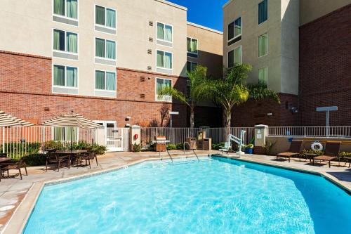 a swimming pool with tables and chairs in front of a building at Hyatt Place San Diego-Vista/Carlsbad in Vista