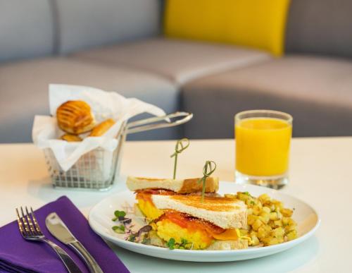 a plate with a sandwich and corn and a glass of orange juice at YOTEL Boston in Boston