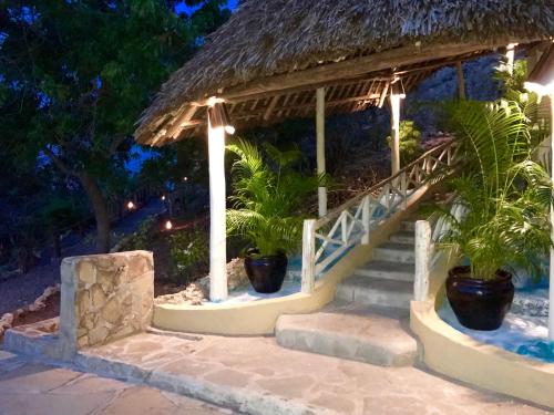 a gazebo with stairs and potted plants at night at Rock and Sea Resort in Watamu