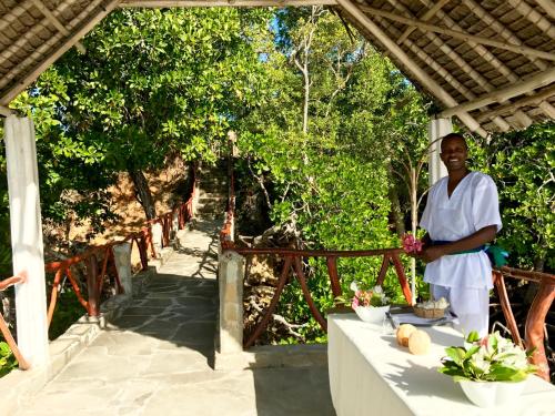a man standing next to a table with flowers at Rock and Sea Resort in Watamu