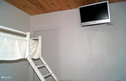 a tv on a wall with a ladder and a chair at Casa Rural El Nacimiento in Benaoján