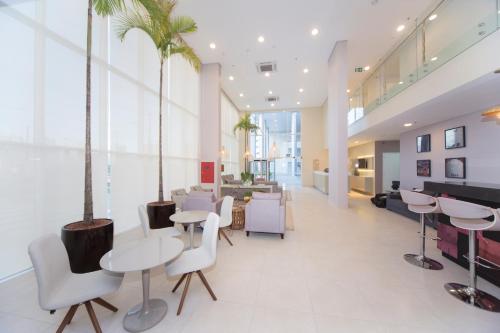 a lobby with tables and chairs and palm trees at NB Hoteis in Aracaju