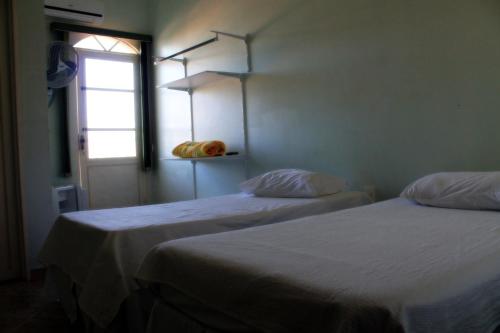 zwei Betten in einem Zimmer mit Fenster in der Unterkunft Pousada Sertão Veredas in Sao Domingos de Goias